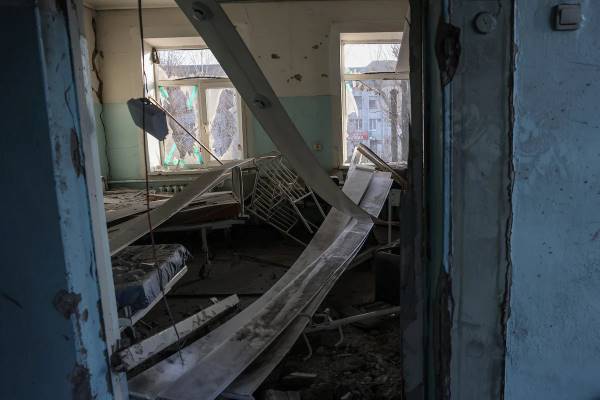 Працівниця лікарні стоїть серед уламків зруйнованого пологового відділення у Вільнянську, Україна